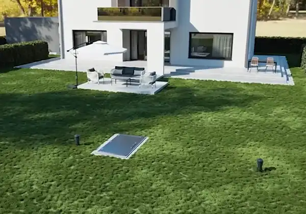 Modern white house with a patio and outdoor seating under a large umbrella on a green lawn.